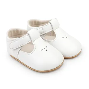 Side view detail of white T-strap baby walking shoes with perforated pattern