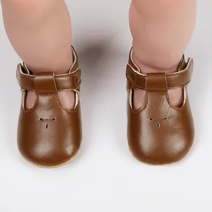 Detailed view of classic brown faux leather baby T-strap shoes with cute flower cutouts