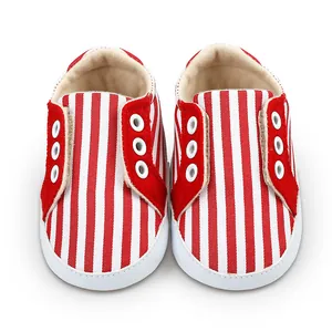 Chaussures de marche pour bébé à rayures rouges et blanches avec semelle souple.