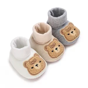 Trois paires de chaussons pour bébé à motif d'ours en tricot souple blanc, beige et gris.