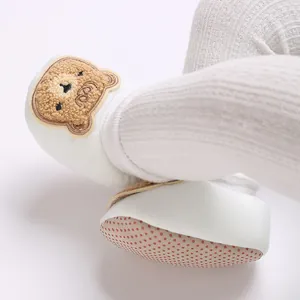 Gros plan sur le patch ours mignon et la semelle antidérapante des chaussures bébé blanches