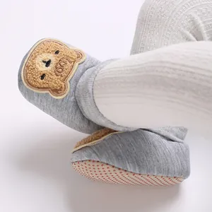 Détail de chaussettes de marche grises pour bébé avec ours et semelle antidérapante.