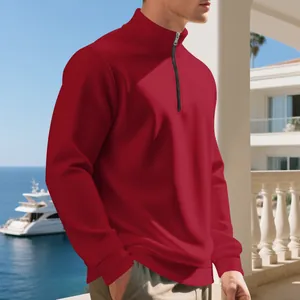 Felpa da uomo rossa con mezza zip in un lussuoso ambiente costiero con vista sul mare.
