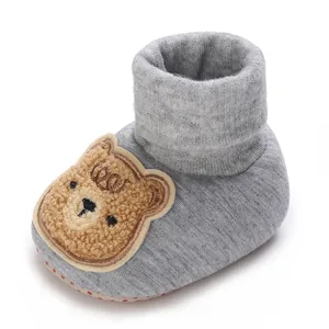 Vue détaillée d'un chausson bébé en tricot gris avec patch ours en peluche et semelle