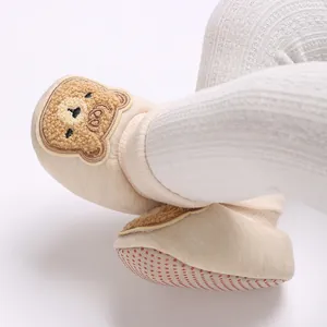 Gros plan d'une broderie d'ours sur des chaussons de bébé antidérapants doux