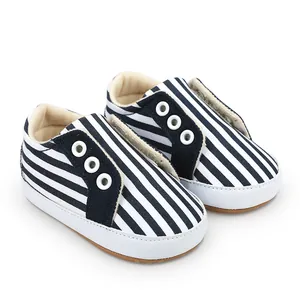 Gros plan de chaussures de marche rayées bleu et blanc pour bébé avec œillets.
