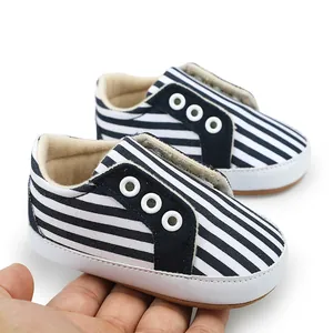 Gros plan sur les chaussures de marche pour bébé à rayures bleu marine et blanc à semelles souples.