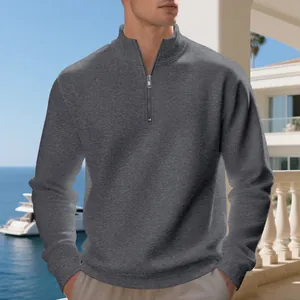 Dettaglio della felpa da uomo grigio scuro con mezza zip in un ambiente esterno soleggiato.