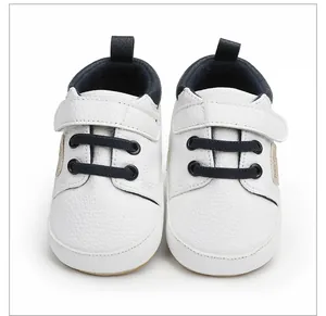 Vista frontal de zapatos blancos para bebé con cordones azul marino y velcro