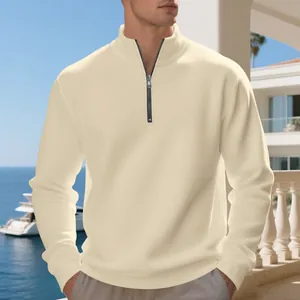 Primo piano di una felpa beige da uomo con mezza zip in un ambiente esterno di lusso