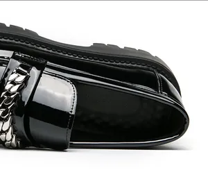 Détail macro du mocassin en cuir verni noir brillant avec une grosse chaîne argentée