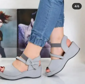 Detaillierte Seitenansicht grauer Keilsandaletten mit Peep-Toe und Schleifen-Design