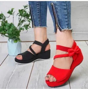 Detailansicht von roten und schwarzen Damen-Keilsandalen mit Schleife und Plateau