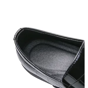 Close-up macro detail showing the black crocodile embossed leather texture of the loafer