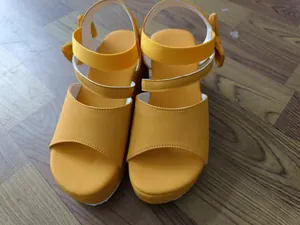 Detailansicht der leuchtend gelben Plateau-Sandalen mit modischer Schleife am Fersenriemen