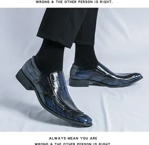 Close-up detail of blue crocodile-embossed patent leather loafers with a pointed toe.