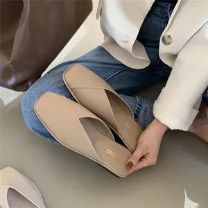Close-up view of elegant women's beige square-toe flat mule slippers held in hand