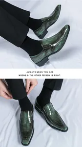 Detailed macro shot of dark green crocodile embossed shiny leather loafers on foot