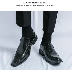 Close-up of black shiny embossed patent leather loafers worn with black trousers
