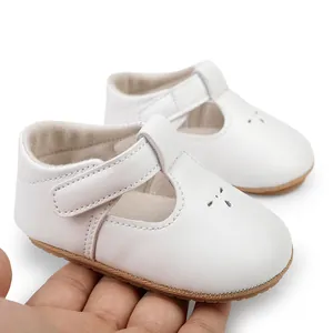 Detail view of white baby T-strap walking shoes held by hand for scale