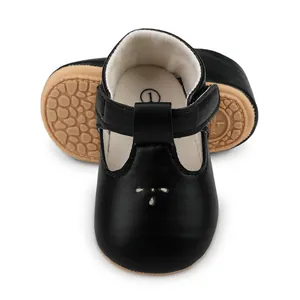 Close-up detail view of black T-strap baby pre-walker shoes with non-slip rubber soles