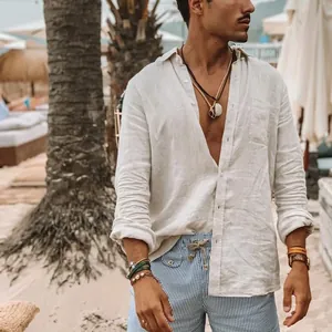 Man met wit los katoenen linnen shirt met lange mouwen in een tropische strandomgeving