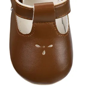 Close-up detail of brown leather baby girl T-strap dress shoe with decorative cutouts