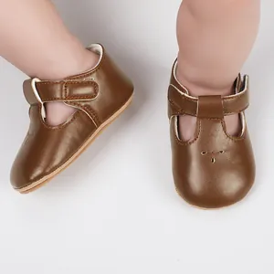 Detailed view of brown PU leather baby shoes with T-strap and decorative flower cutouts on toes