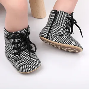 Gros plan de chaussures de marche pour bébé à motif pied-de-poule noir et blanc avec lacets