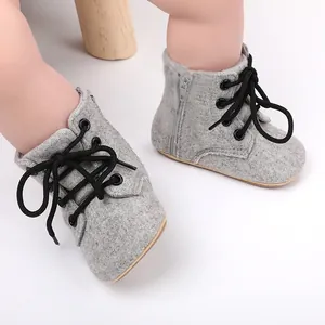 Détail de chaussures de marche pour bébé en tissu gris avec fermeture éclair et lacets noirs