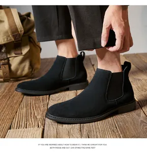 Detail view of men's black suede Chelsea boots worn on a rustic wooden floor deck