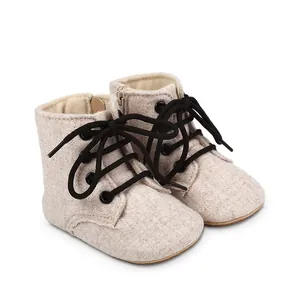 Détail de bottines de marche beige pour bébé avec lacets noirs et fermeture éclair