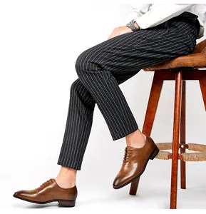 Side view of men's brown brogue shoes styled with pinstripe trousers on a stool