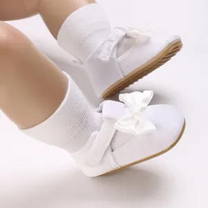 Close-up view of white soft sole baby walking shoes decorated with elegant ribbon bows