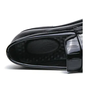 Detailed macro view of black patent leather loafers showing embossed crocodile skin texture