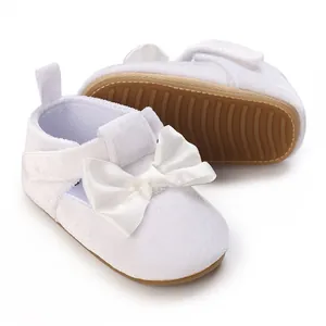 Close-up of white baby girl walker shoes with large bow and soft non-slip sole.