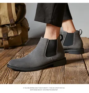 Close-up of stylish grey suede Chelsea boots for men worn on a rustic wooden background