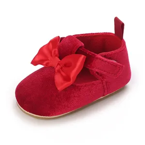 Close-up of red velvet baby pre-walker shoe with a large satin bow and velcro strap