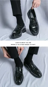 Detailed view of men's black patent leather tassel loafers with embossed crocodile pattern