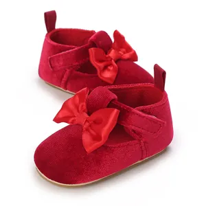 Close-up detail of soft red velvet baby pre-walker shoes featuring a satin bow accent