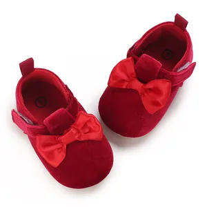 Detailed view of red velvet baby shoes featuring a large satin bow and soft sole.