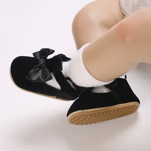 Detailed macro shot of soft-soled black velvet baby walking shoes with ribbon bow