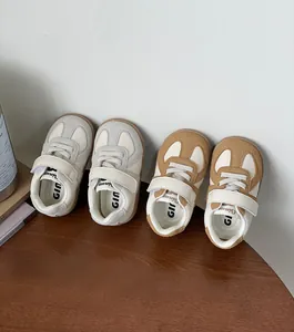 Close-up of baby sneakers in tan and off-white colors on a wooden surface