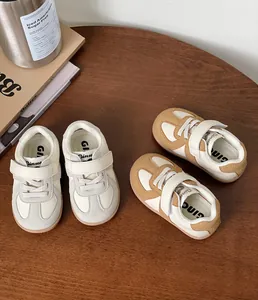 Overhead view of two pairs of soft-soled toddler sneakers displayed on a wooden table