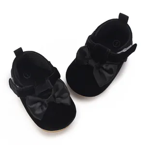 Close-up of black velvet infant walker shoes featuring decorative large satin bows.