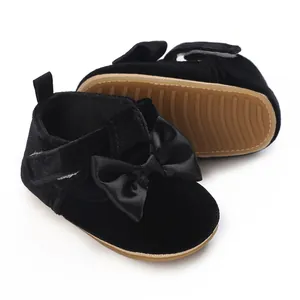 Detailed view of black velvet baby walking shoes with a satin bow and soft sole