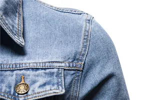 Macro view of blue denim jacket shoulder with precise stitching and metal button.