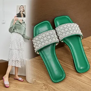 Detailed macro view of green square toe flat slides with pearl and rhinestone embellishments