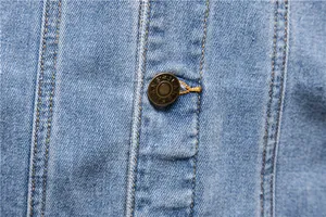 Detailed view of the metal button and stitching on a classic men's blue denim jacket