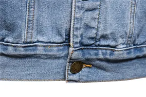 Close-up of metal button and hem stitching on a light blue slim-fit men's denim jacket
